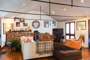 Ein gemütliches Wohnzimmer mit Kamin, einer Couch, einem Fernseher und einem großen Fenster.