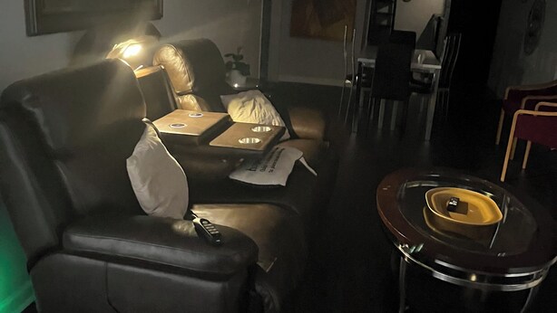 Un salon avec un canapé, une table basse, un ventilateur de plafond et, au fond, un coin repas.