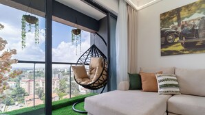 Una sala de estar moderna con un ventanal grande, una silla colgante, un sofá y un cuadro en la pared.