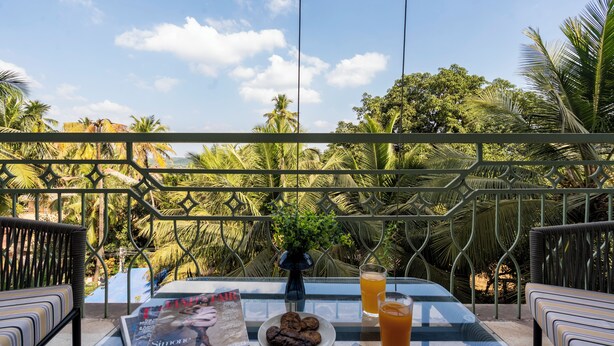Ein Balkon mit Tisch, einer Zeitschrift, Keksen und einem Glas Orangensaft.
