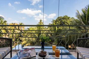 Ein Balkon mit Tisch, einer Zeitschrift, Keksen und einem Glas Orangensaft.