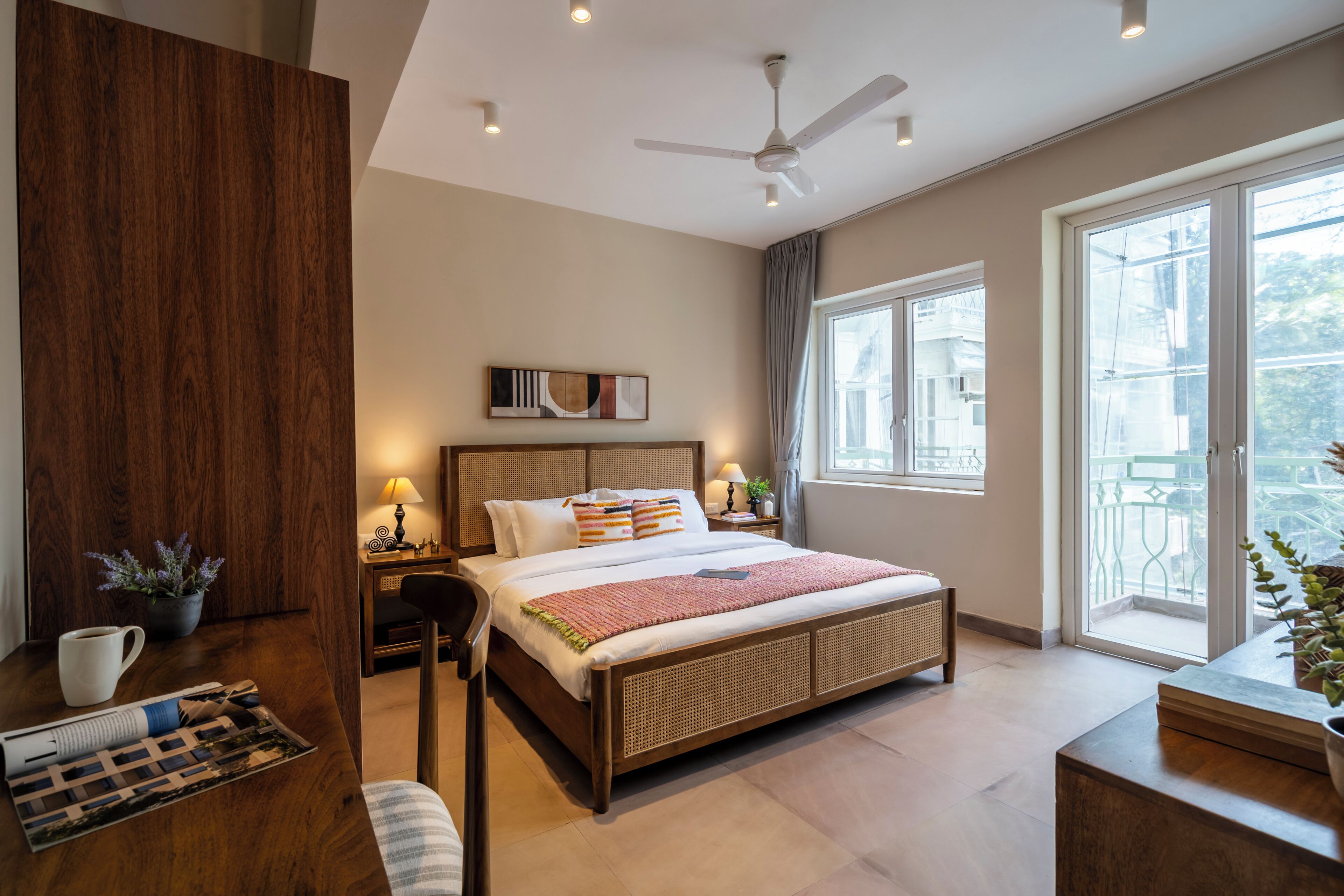 Ein Schlafzimmer mit Bett, Nachttischen, Deckenventilator, Fenster und Ausblick nach draußen.