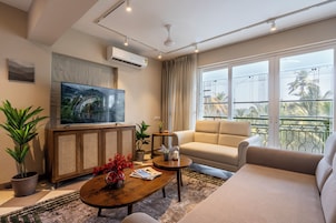 Una sala de estar moderna con televisor de pantalla plana, un sofá, una mesa de centro y plantas en macetas.