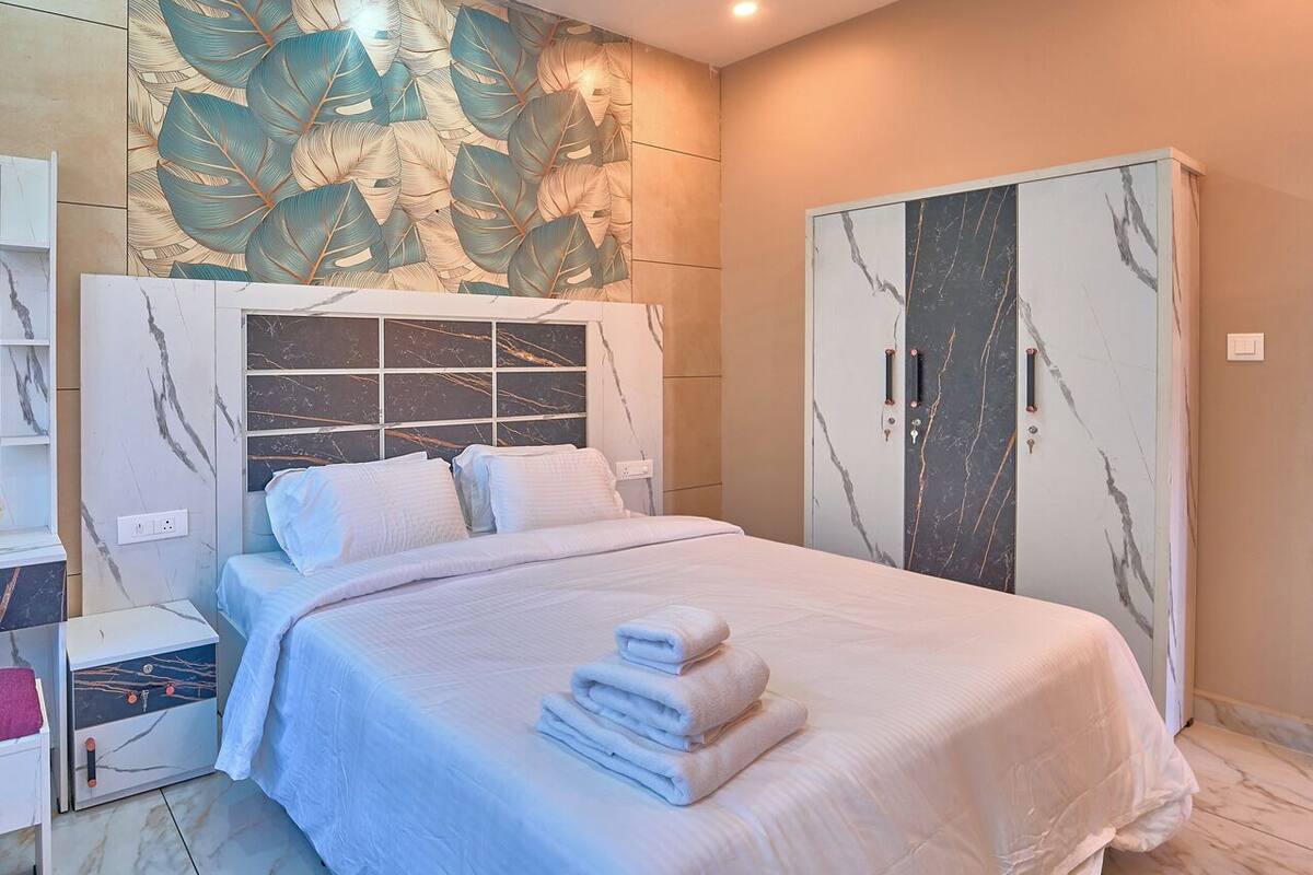 Een hotelkamer met een bed, een kledingkast en een muur met een bladmotief.