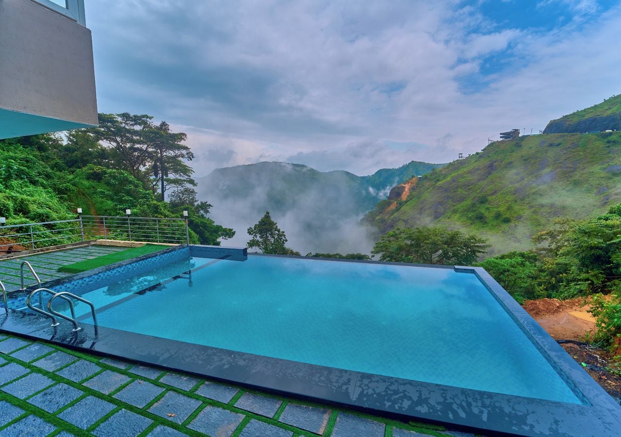 Una piscina rectangular con superficie de agua azul cristalina, rodeada por una solana pavimentada con barandilla metálica.