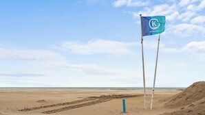 A beach with a flag on two poles, a sandy area, and a clear sky. - Duin & Kust Residence - 50 metres from the beach, promenade and dunes (Oostduinkerke)