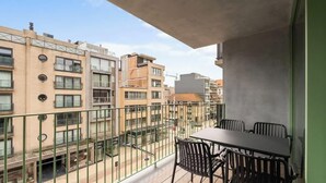 A balcony with a table and chairs, overlooking a cityscape with multiple buildings. - Duin & Kust Residence - 50 metres from the beach, promenade and dunes (Oostduinkerke)