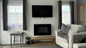 Un salon équipé d’un téléviseur à écran plat, d’une cheminée, d’un canapé et d’une petite table.