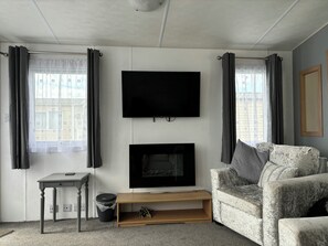 Ein Wohnzimmer mit Flachbildfernseher, Kamin, Sofa und einem kleinen Tisch.