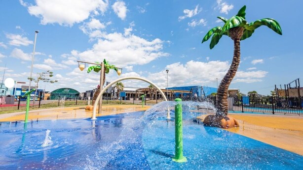 Un parc aquatique doté d’une grande installation aquatique, d’une sculpture représentant un palmier et d’une structure de jeux pour enfants.
