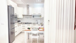 Eine moderne Küche mit weißen Schränken, einem Edelstahlkühlschrank, einer Mikrowelle und einem Gasherd.