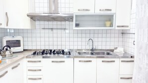 A modern kitchen with white cabinets, a gas stove, a stainless steel sink, and a microwave. - Cà 4 Nevodi Chiara by Ca-Sa Check (Chioggia)