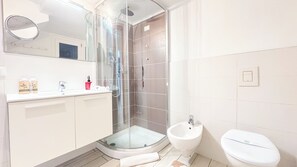 Une salle de bain moderne avec une douche à parois de verre, un lavabo et des toilettes.