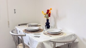 Une table à manger dressée avec des assiettes, un vase rempli de fleurs et un interrupteur fixé au mur.