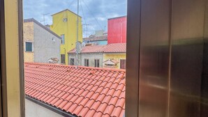 On aperçoit un bâtiment avec un toit recouvert de tuiles rouges, un bâtiment jaune et, au fond, un bâtiment rouge.