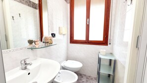 Une salle de bain équipée d’un lavabo, d’un bidet, de toilettes et d’une fenêtre.