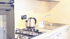 Une cuisine équipée d’une cuisinière à gaz, d’une bouilloire, d’un évier et d’une prise électrique murale.