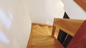 Eine Holztreppe mit geschwungener Form, die zu einer dunklen Tür führt.