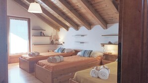 Ein Schlafzimmer mit zwei Betten, Holzbalken, einem Fenster und Regalen mit Gegenständen.