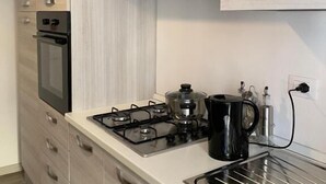 Une cuisine moderne équipée d’un four encastré, d’une cuisinière à gaz et d’une hotte en acier inoxydable.