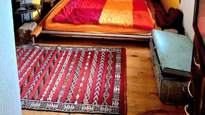 A bed with a colorful quilt, a patterned wall tapestry, and a small table with a lamp. - Holiday Home 'Charming' with Shared Terrace and Wi-Fi (Neckargemünd)