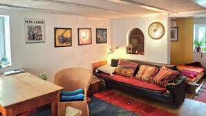 A living room with a sofa, a wicker chair, a table, and a wall with framed pictures. - Holiday Home 'Charming' with Shared Terrace and Wi-Fi (Neckargemünd)