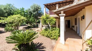 A house with a covered patio, a garden with various plants, and a clear blue sky. - Villa 'Panada' with Private Pool, Wi-Fi, and Air Conditioning (Pollença)
