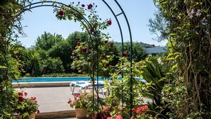 A pool area with a pergola covered in flowers, lounge chairs, and a clear sky. - Villa 'Panada' with Private Pool, Wi-Fi, and Air Conditioning (Pollença)
