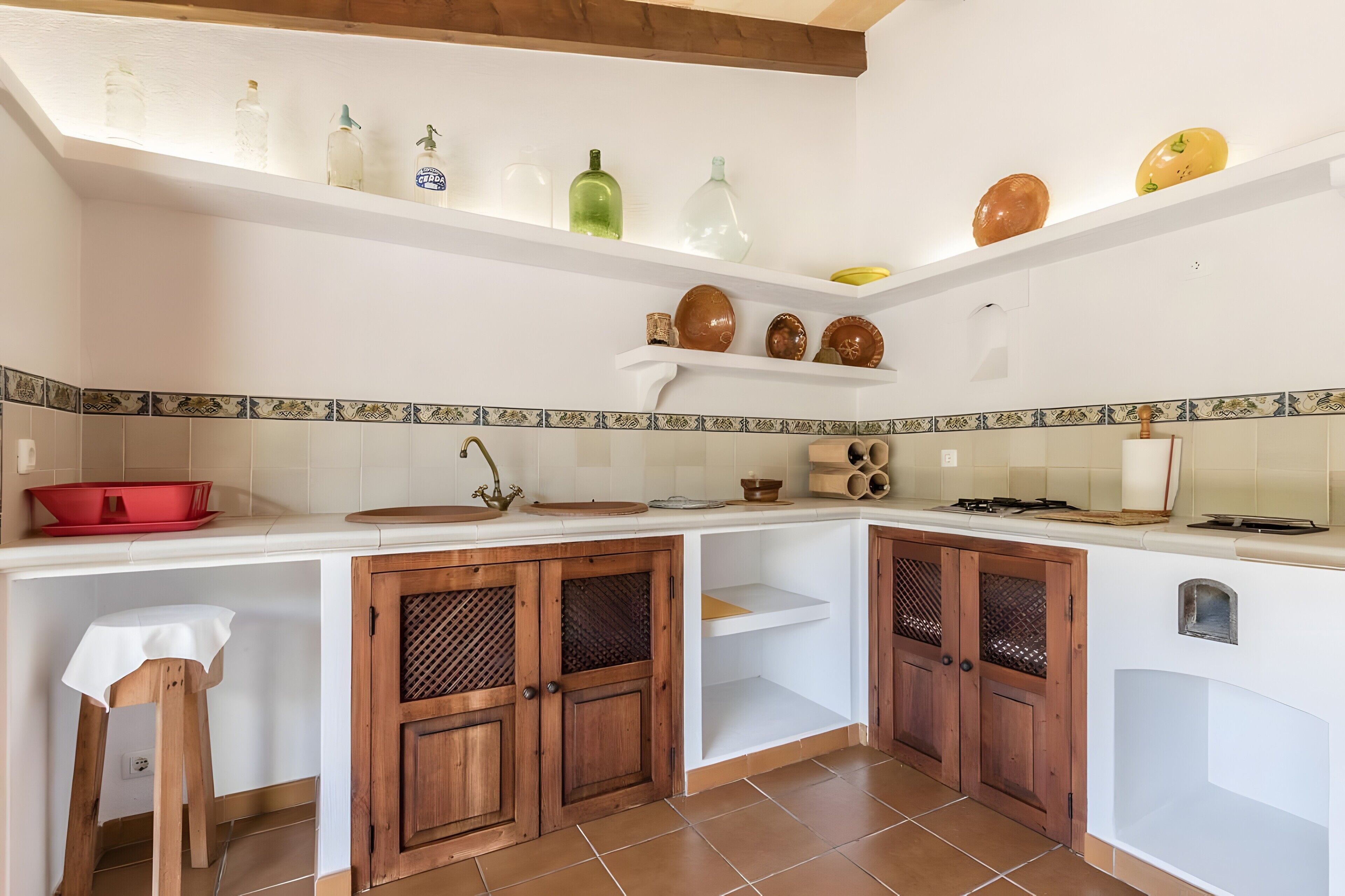 A kitchen with white cabinets, wooden doors, a red bowl, and various kitchen utensils.