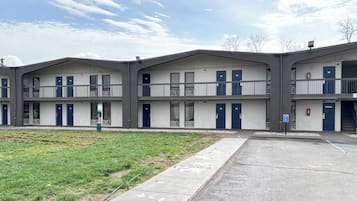 Un motel de varios pisos con techo plano, balcones y un área de estacionamiento.