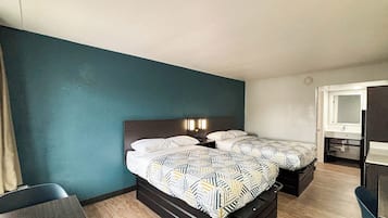 A hotel room with two beds, a desk, a chair, and a mirror.