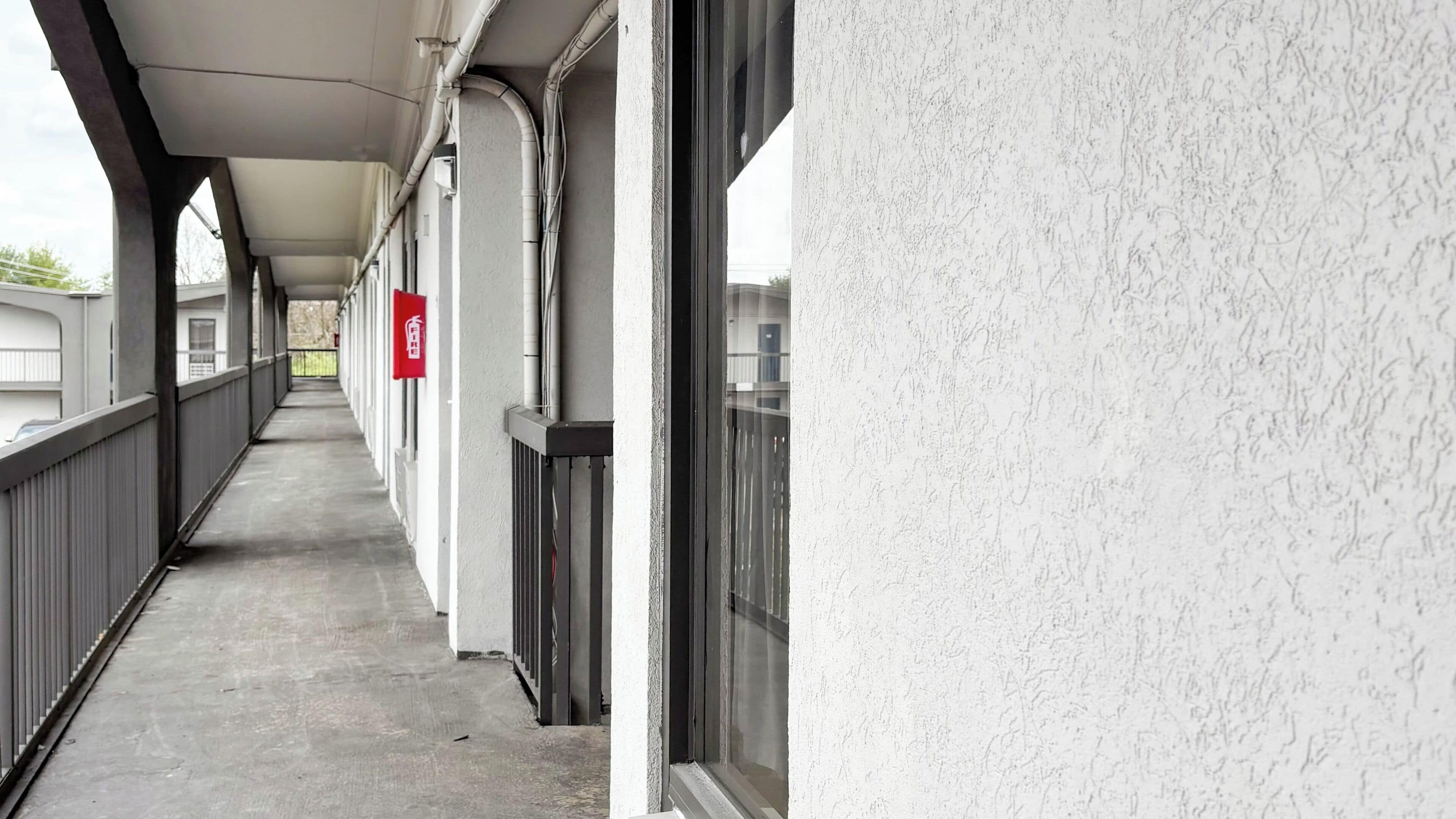 A corridor with a fire extinguisher, a window, and a door.