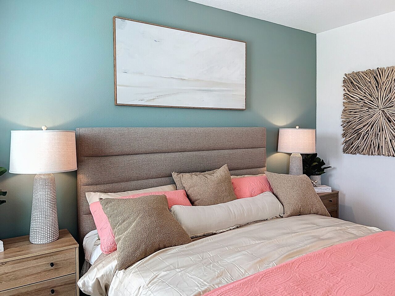 A bedroom with a bed, bedside tables, lamps, a wall art piece, and a decorative wall piece.