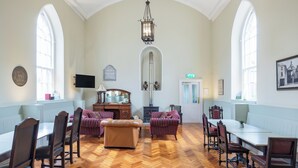 A spacious room with a herringbone floor, wooden furniture, and large windows.