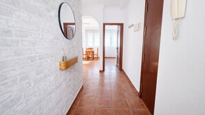 A hallway with a brick wall, a wooden door, and a mirror. - Apartamento Arrumbadores con terraza en Conil (conil de la frontera)