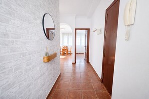 A hallway with a brick wall, a wooden door, and a mirror. - Apartamento Arrumbadores con terraza en Conil (conil de la frontera)