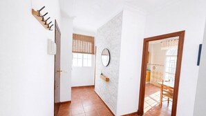 A hallway with a coat rack, a mirror, a door leading to a room, and a window with blinds. - Apartamento Arrumbadores con terraza en Conil (conil de la frontera)