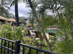 A tropical resort with a pool, palm trees, and thatched-roof structures.