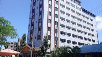 A multi-story hotel with a central courtyard, surrounded by greenery and other buildings.