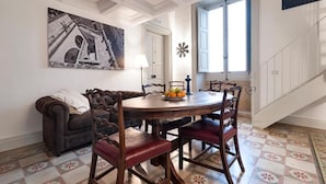 Un espace repas comprenant une table ronde, des chaises, un canapé, un tableau et un escalier.