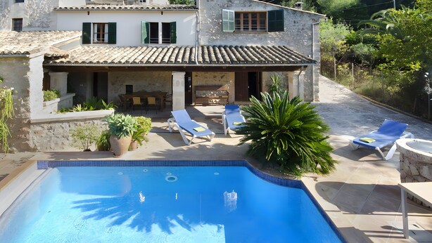 A swimming pool with lounge chairs, a stone building with a tiled roof, and surrounding greenery. - Holiday Home "Camp Redo" with Mountain View, Pool, Garden, Terrace & Wi-Fi (Illes Balears)