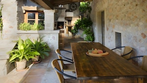 A rustic outdoor dining area with a wooden table, wicker chairs, and potted plants. - Holiday Home "Camp Redo" with Mountain View, Pool, Garden, Terrace & Wi-Fi (Illes Balears)
