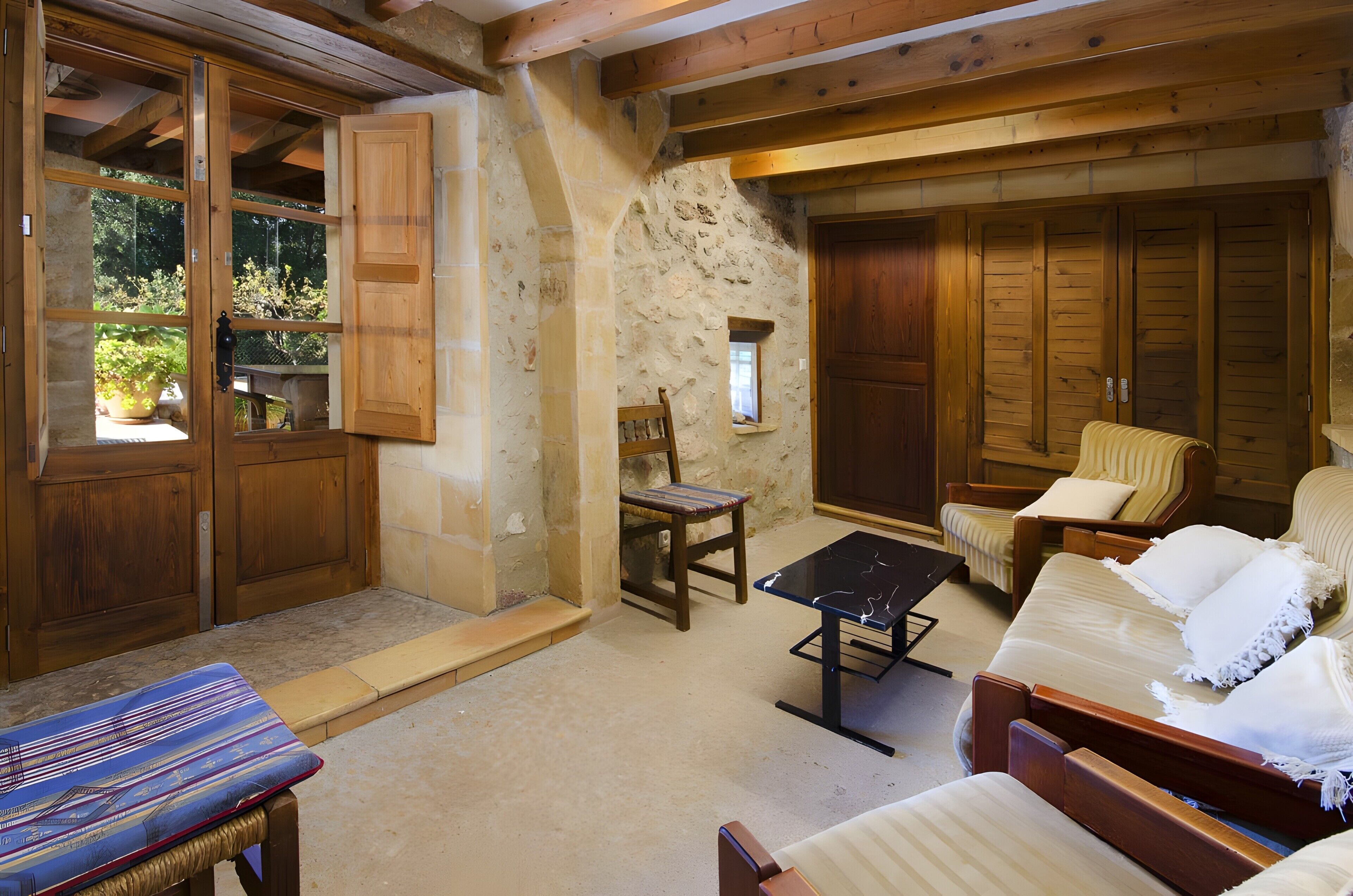 A rustic room with a stone wall, wooden furniture, and a large wooden door.