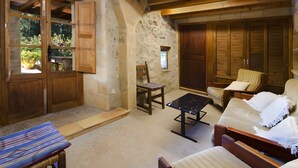 A rustic room with a stone wall, wooden furniture, and a large wooden door. - Holiday Home "Camp Redo" with Mountain View, Pool, Garden, Terrace & Wi-Fi (Illes Balears)