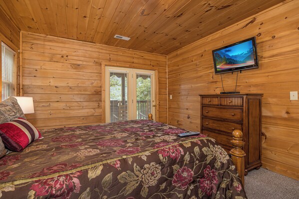 A wooden-paneled room with a bed, dresser, and television. - Residing In The Highlands (GATLINBURG)