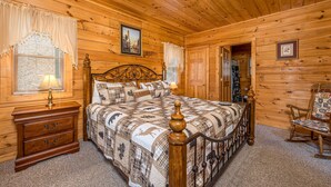 A wooden cabin bedroom with a bed, nightstand, dresser, and a rocking chair. - Residing In The Highlands (GATLINBURG)