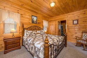 Une chambre dans une cabane en bois, avec un lit, une table de chevet, une commode et un fauteuil à bascule.