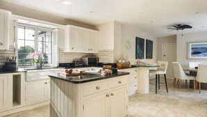 Uma cozinha com armários brancos, bancada preta, micro-ondas e um espaço de refeições com cadeiras e uma mesa.