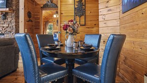Un interno in legno con un tavolo rotondo, poltrone in pelle blu e un vaso di fiori.
