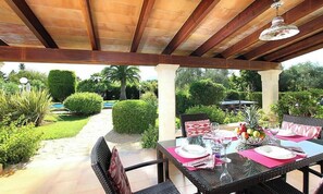 An outdoor patio with a table set for dining, surrounded by greenery and a pool. - Country Home "Can Moreno" with Pool, A/C, Wi-Fi, Garden & Terrace (Illes Balears)